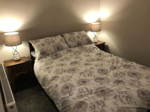 a bed in a bedroom with two night stands and two lamps at Modern 3 Bed Barn Conversion in Great Urswick in Great Urswick