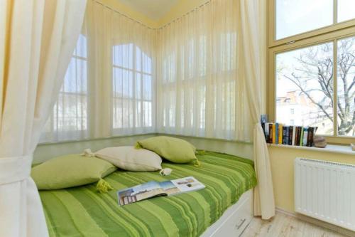 Schlafzimmer mit einem Bett mit grüner Bettwäsche und einem Fenster in der Unterkunft Villa Waldschloss, App 05 in Heringsdorf