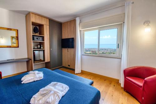 ein Schlafzimmer mit einem blauen Bett und einem roten Stuhl in der Unterkunft Colleverde Park Hotel in Agrigento