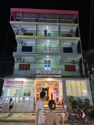 Vang Vieng Freedom View Hostel في فانغ فينغ: مبنى طويل فيه ناس تقف امامه