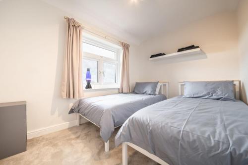 a bedroom with two beds and a window at Corner Cottage in Matlock