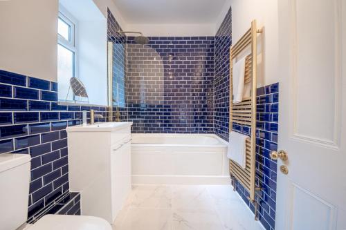 a blue tiled bathroom with a tub and a toilet at Corner Cottage in Matlock