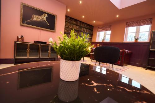 a room with a table with a vase with flowers on it at Little Hayes in Lyndhurst