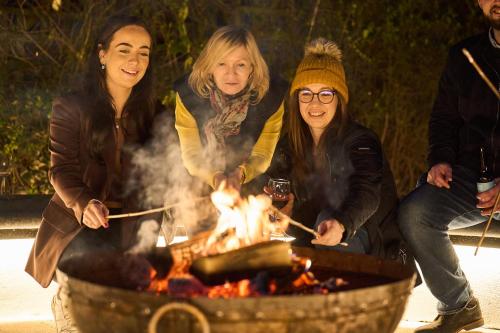 a group of three women standing around a fire at Little Hayes in Lyndhurst