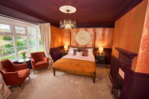 a bedroom with a bed and two chairs and a chandelier at Little Hayes in Lyndhurst