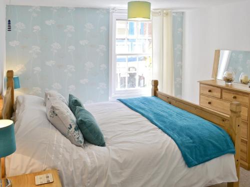 a bedroom with a bed with blue walls and a window at Seashells in Cromer