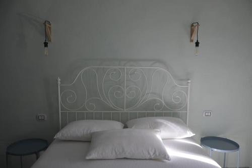 a white bed with two pillows and two tables at GarganoMareBorghi ospitalità diffusa in Vico del Gargano