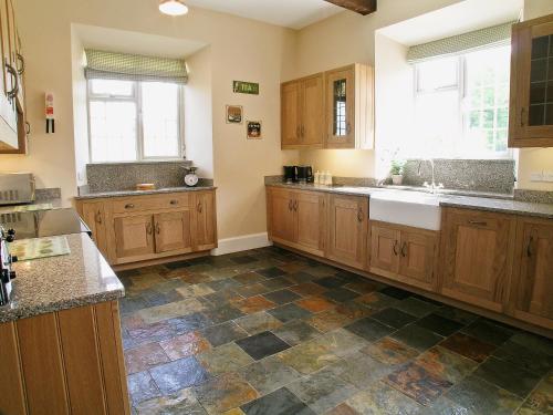 a kitchen with wooden cabinets and a tile floor at Armswell House in Ansty