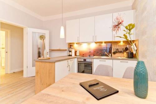 uma cozinha com armários brancos e uma mesa de madeira em Villa Anna, App 12 em Ahlbeck