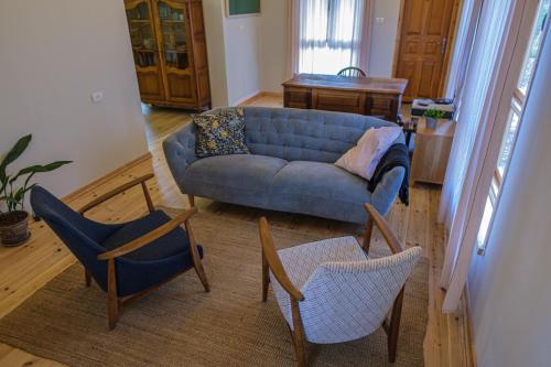 sala de estar con sofá azul y 2 sillas en הבקתה על השדות, en Kefar Pines