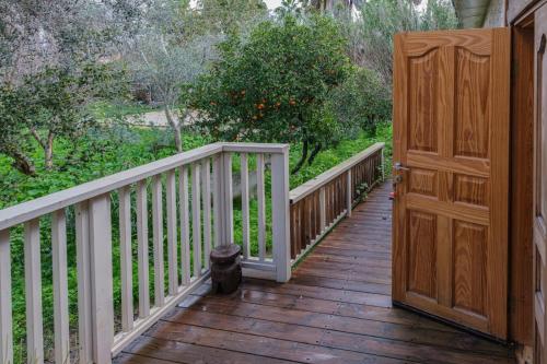 una porta aperta su una veranda in legno con ingresso a un cortile di הבקתה על השדות a Kefar Pines
