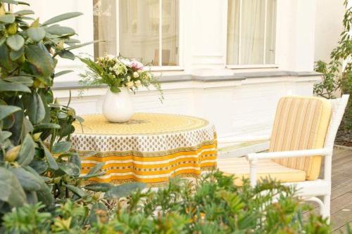 une table avec un vase de fleurs et une chaise dans l'établissement Villa Astrid, T3 Anklam, à Bansin