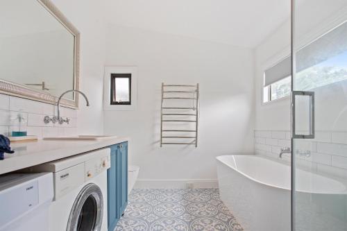 a bathroom with a tub and a sink and a washing machine at Blue House Bendigo in Bendigo