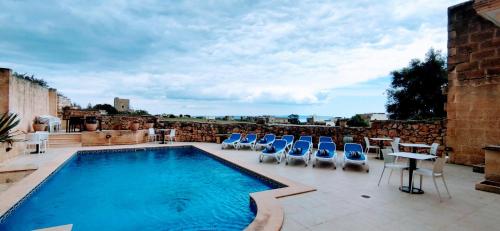 a swimming pool on a patio with chairs and a table at Warda Accommodation in Xewkija