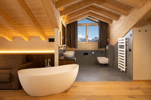 un bagno con una grande vasca e due lavandini di Camino Rustic Chic Hotel a Livigno