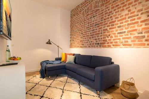 a living room with a blue couch and a brick wall at Villa Bellevue App 05 in Heringsdorf