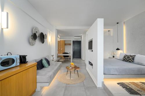 George & Joanna Suites Santorini في فيرا: غرفة معيشة مع أريكة وسرير في غرفة