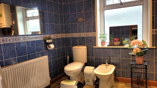 a blue tiled bathroom with a toilet and a sink at Another sweet home in Bradford