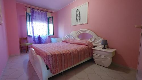 a bedroom with a white bed and a pink wall at Residence Leonardo in Silvi Marina
