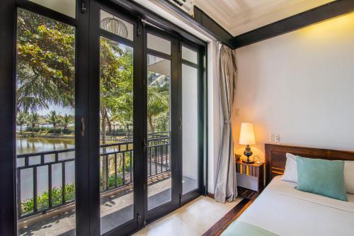 a bedroom with a bed and a window with a view at Tra Que Mansion in Hoi An