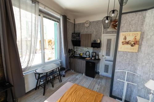 Habitación con cocina con mesa y ventana. en Studio Malou, cuisine, salle d'eau, terrasse amenagée, en Olliergues