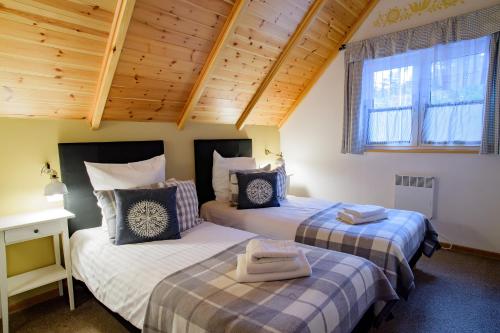 two beds in a room with wooden ceilings at Domki Kaszuby - jezioro las i zoo w Szarlocie in Kościerzyna