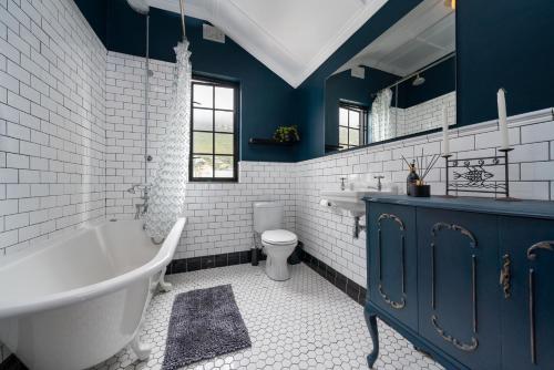 bagno con pareti blu, vasca e servizi igienici di ‘The Black Pearl’ - Surfers Corner, Muizenburg a Città del Capo
