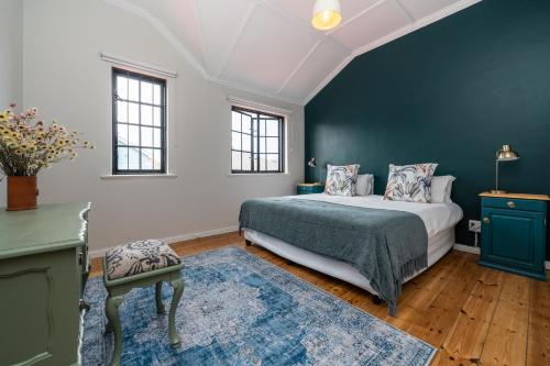 a bedroom with a bed and a blue wall at ‘The Black Pearl’ - Surfers Corner, Muizenburg in Cape Town