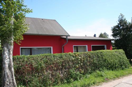 una casa roja con un seto delante de ella en Ferienhaus Moeller, en Wustrow