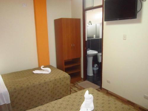 a room with two beds and a bathroom with a toilet at Hotel Plaza Trujillo in Trujillo