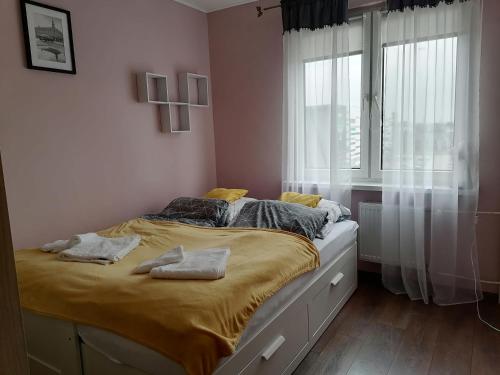 a bedroom with a bed with yellow sheets and a window at Apartament Arena in Zgorzelec