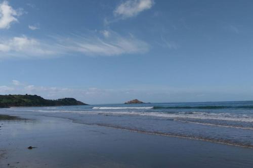 une plage de sable avec des vagues dans l'océan dans l'établissement Maison presqu'île Hillion centre bourg et proche de la Mer, à Hillion