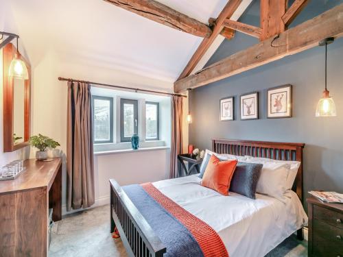 een slaapkamer met een bed, een bureau en ramen bij Weavers Cottage in Marsden
