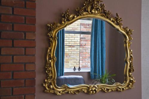 an ornate gold mirror on a wall with a window at The Abbey House Hotel in Reading
