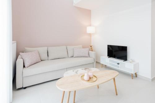 a white living room with a couch and a table at ESTEA Quality Living in Volos