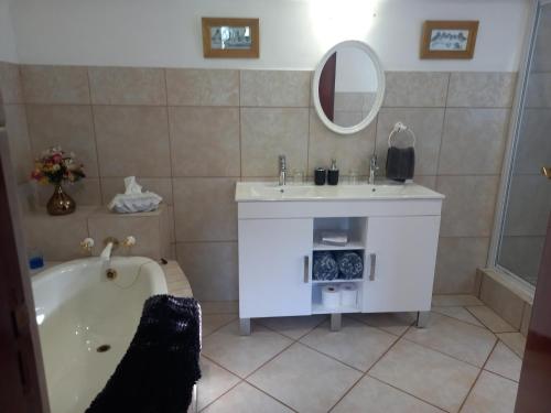 a bathroom with a tub and a sink and a mirror at Mulligans Guest Lodge in Hermanus