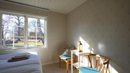 a bedroom with a bed and a window and chairs at Mormors Pensionat Strandhagen in Stora Rör