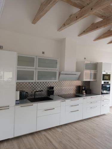 a white kitchen with white appliances and wooden floors at Constanza in Plau am See