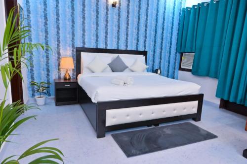 - une chambre avec un lit et des rideaux et des plantes bleus dans l'établissement Hotel Wild Rose, à New Delhi
