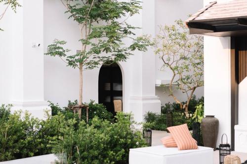a white house with a courtyard with trees at Burirattana Hotel-An Adults Only Hotel in Chiang Mai