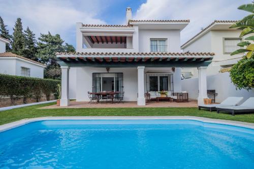 a villa with a swimming pool in front of a house at GINVA - Villa Puerto Sherry in El Puerto de Santa María