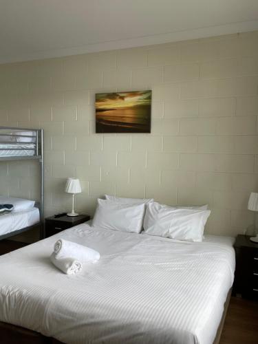 a white bed with a towel on top of it at Siesta Villa in Jindabyne