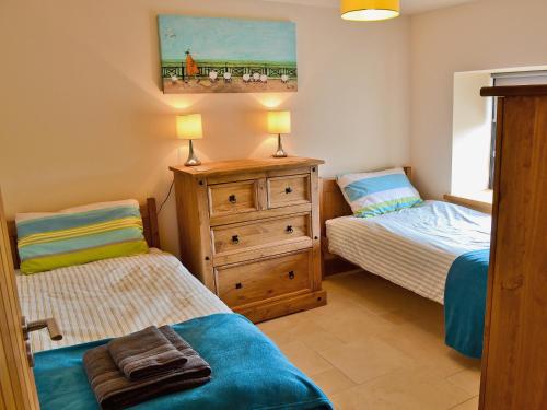 a bedroom with two twin beds and a dresser at Pen Yr Allt in Rhosneigr