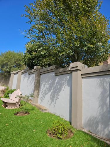 a fence with a tree on top of it at Three Stones Executive Apartments in Maseru