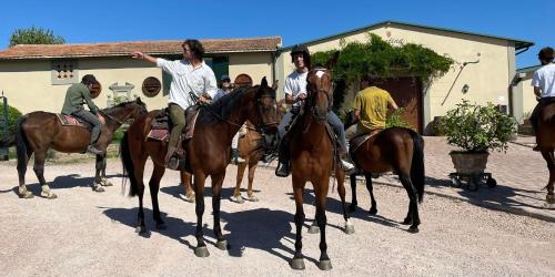 a group of men riding on horses in front of a building at La Ghirlanda Wine Resort in Saragano