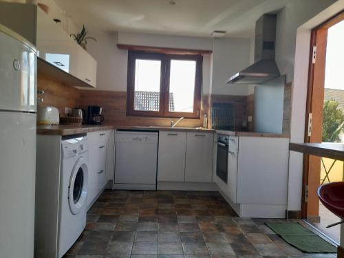 une cuisine avec des armoires blanches et une laveuse et une sécheuse dans l'établissement Appart 4 pers refait neuf 90m2 avec balcon, à Baldenheim