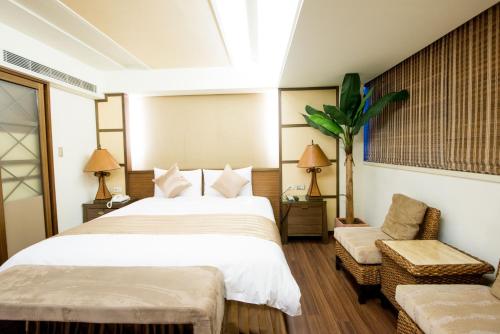 ein Schlafzimmer mit einem großen Bett und einem Stuhl in der Unterkunft Shin Yuan Celeb Metro Hotel in Hsinchu