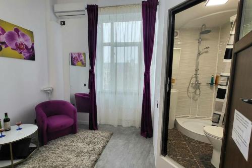 a bathroom with a purple chair and a bath tub at Garsoniera centru vechi English park in Craiova