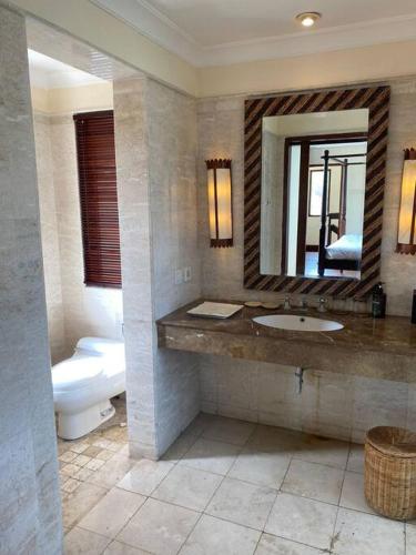 a bathroom with a sink and a toilet and a mirror at Jimbaran BeachStroll Villa (3BR) in Jimbaran
