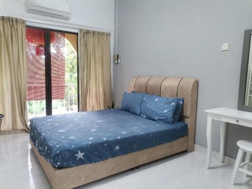 Schlafzimmer mit einem Bett mit blauer Bettwäsche und einem Fenster in der Unterkunft EBH INN in Malakka